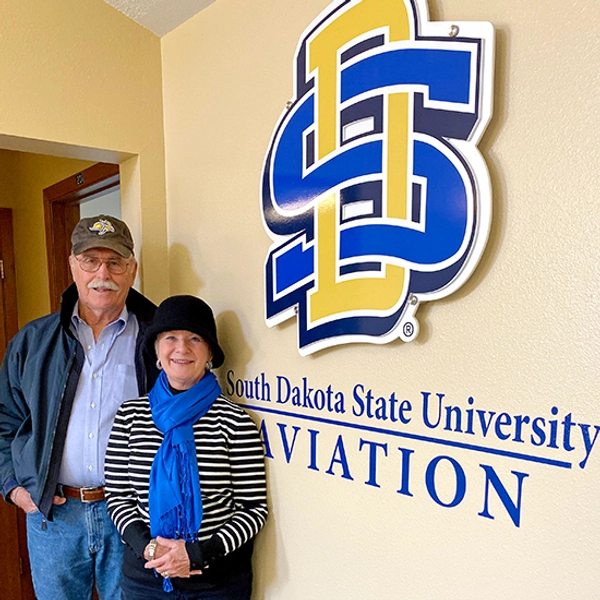 A couple posing by a SDSU Aviation sign