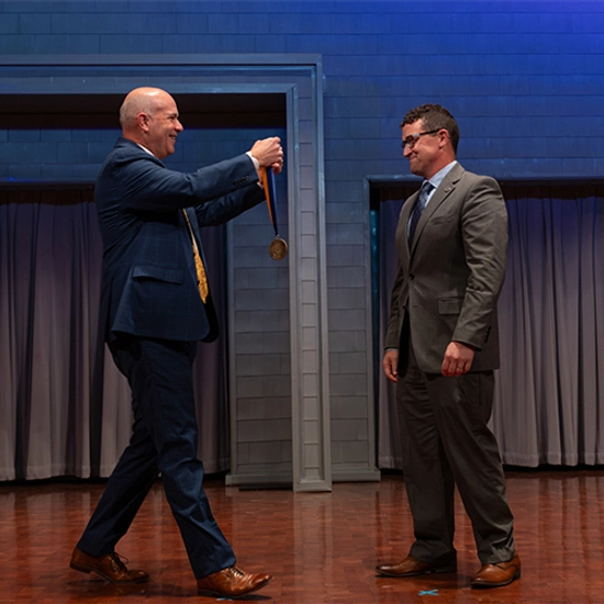 Provost places the medallion around the endowed position holder's neck at the investiture ceremony