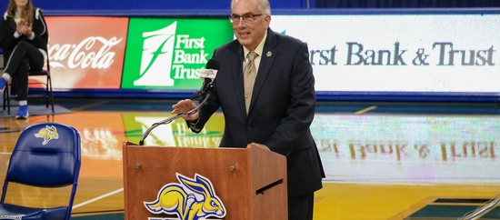 Photo of President Dunn smiling at the podium during the announcement