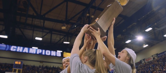 Members of Jackrabbits womens basketball team celebrating, holding up the WNIT trophy.