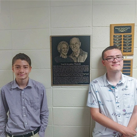 Eric and Lucas Wintrode stand next to a plaque for Virgil and Josephine Wintrode on the SDSU campus..