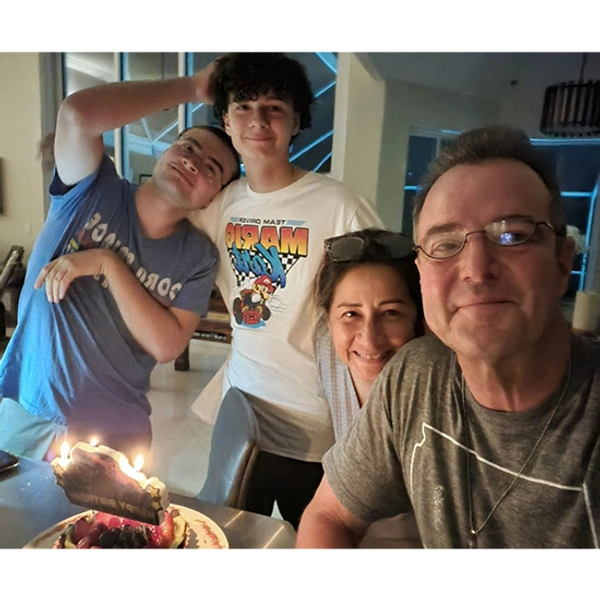 The Wintrode family posing for a family photo with a lit candled cake in the foreground.