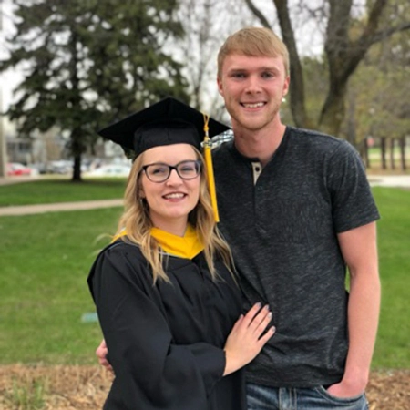 Sydney, dressed in a graduation cap and gown, and Nathan Adrian smile for the camera after she received her masters degree.
