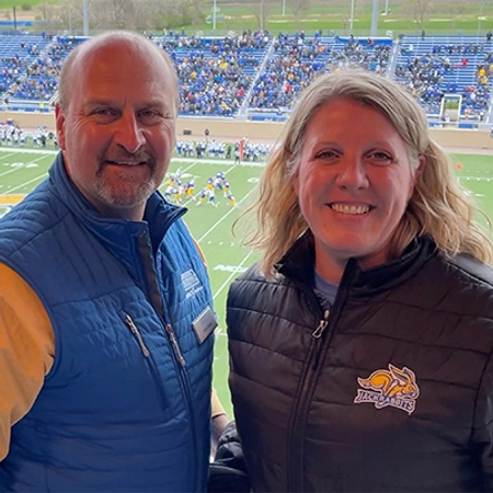 A man and a woman smiling at an SDSU football game