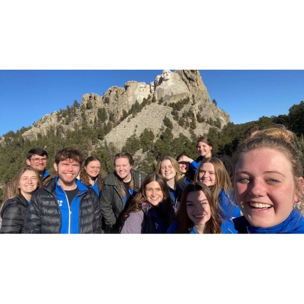 Group of sdsu choir members smiling in front of mt. rushmore