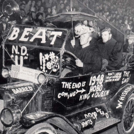 Historic photo of the bummobile with students inside of it with a crowd behind it