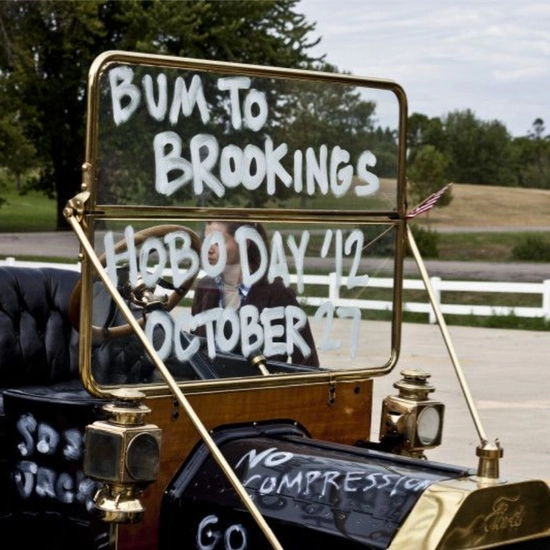 Bummobile windows with painted words reading "bum to brookings, hobo day '12"