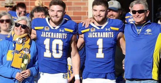 Fred and Linda Janke stand with their twin boys dressed in their football jerseys at an sdsu parents game