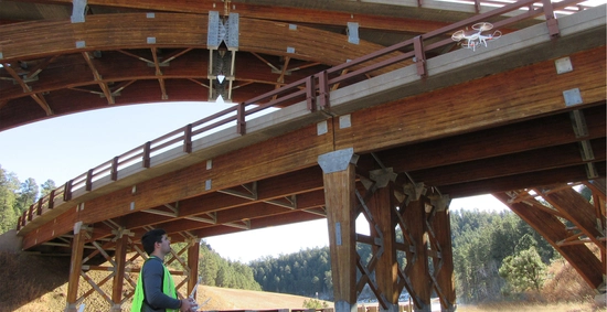 A man flying a drone by a bridge