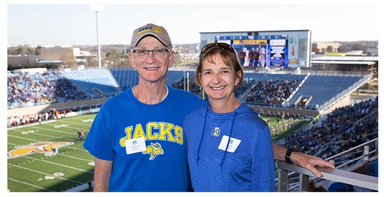 Gordon Niva and Susan Lahr at an SDSU football game with the field in the background