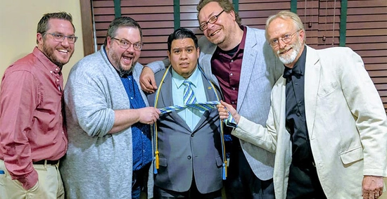Robert stands in the middle of four South Dakota State University professors/instructors as they all smile while pulling on his tie.