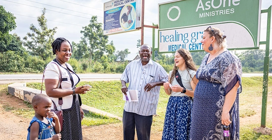 Tanna Becker stands outside with a group of people in Africa in front of an AsOne ministries sign