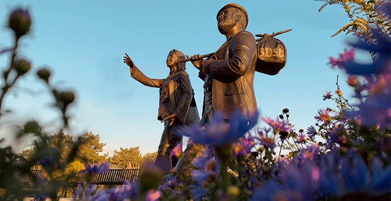 A photo of the Weary Wil and Dirty Lil statues with flowers in the front
