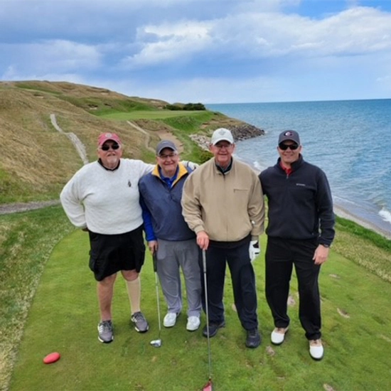 4 men pose for a photo on a golf course
