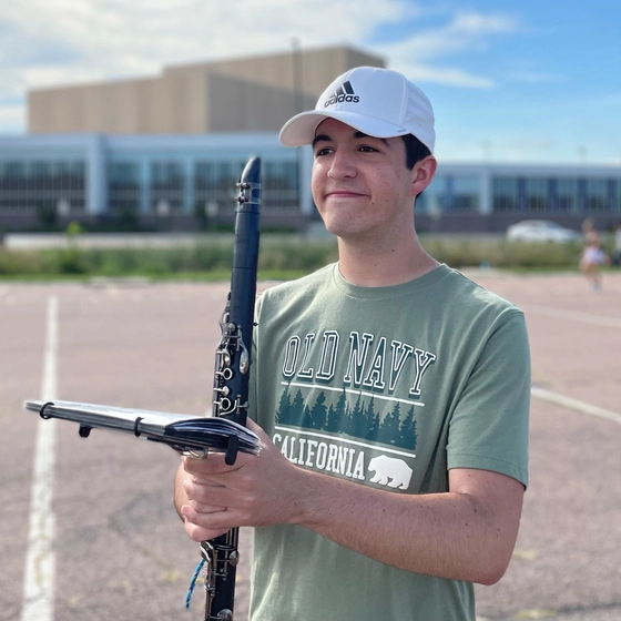 Michael Garafola smiles at Pride of the Dakotas practice, holding a clarinet