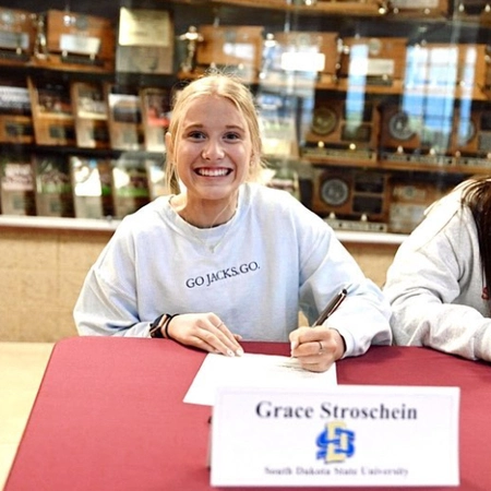 grace stroschein smiling and signing a piece of paper