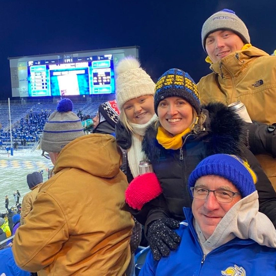 Julie and Marc Mooney smile with family members at a jackrabbit football game