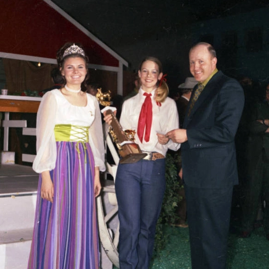 Historic photo of a Little I competition, a man handing an award to two females