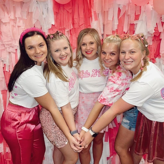 maddie with friends at a pink sorority event, holding hands in the middle