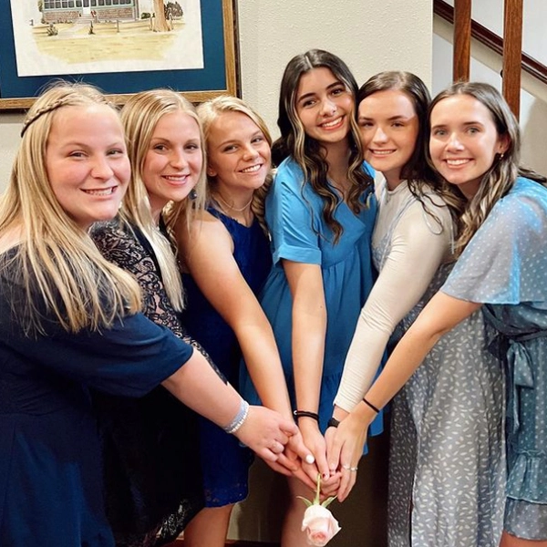 maddie stands with other sorority girls as they put their hands together in the middle