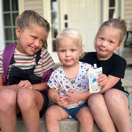 3 young sisters are sitting on the front step of a house while smiling