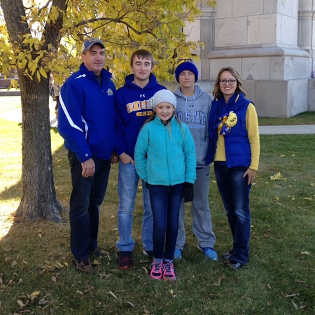 Marc and Julie Mooney standing with their children in front of the campanile on Hobo Day.