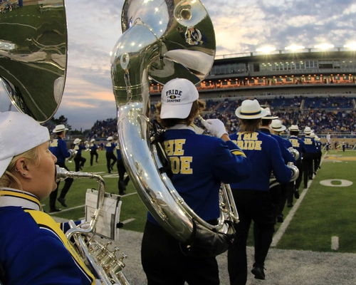 Wide angle photo of the Pride of the Dakotas at the football stadium with the stands of Dana J. Dykhouse stadium in the background