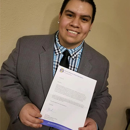 Robert Escamilla proudly smiles while holding up his South Dakota State University acceptance letter.