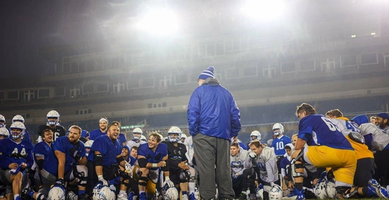 coach stig speaks to his football team after a game with hazy foggy weather