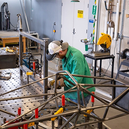 Student working in a engineering lab with machinery all around him.