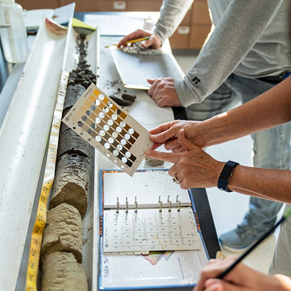 Close up image of hands working on a research project in a classroom.