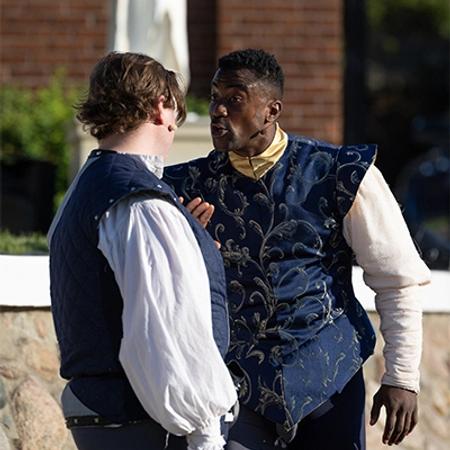 Two men intensely performing wearing Shakespearean clothing.