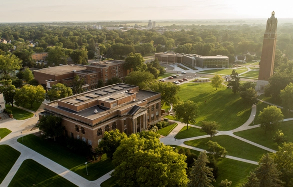 An aerial view of South Dakota State University with brick academic buildings, winding paths, broad lawns, and the campanile.
