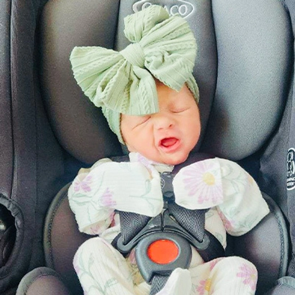 A small child wearing a large green bow.