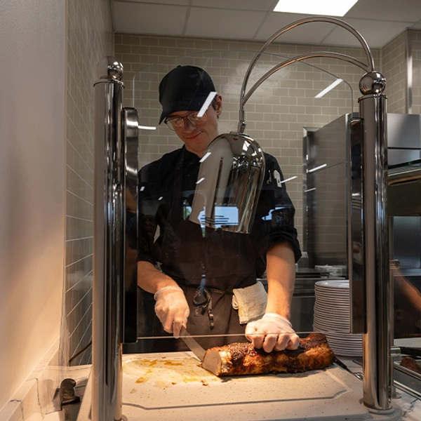 A chef at Larson Commons cutting slices of meat.