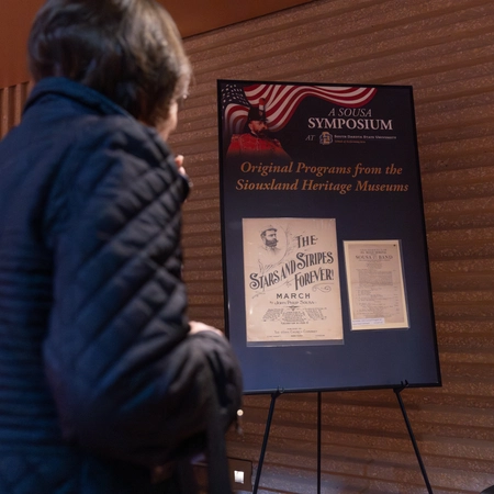 A person stands looking at a poster board on an easel.