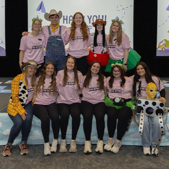 State a thon members stand on stage, smiling together.