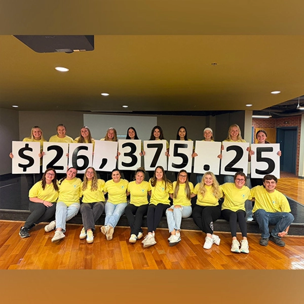 State a thon members stand together holding up signs that spell out the numbers $26,375.25