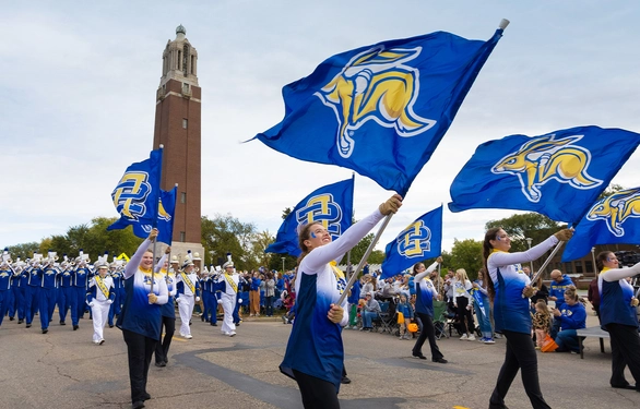 The Pride of the Dakotas marches down Medary Avenue on Hobo Day, with the Campanile in the background.