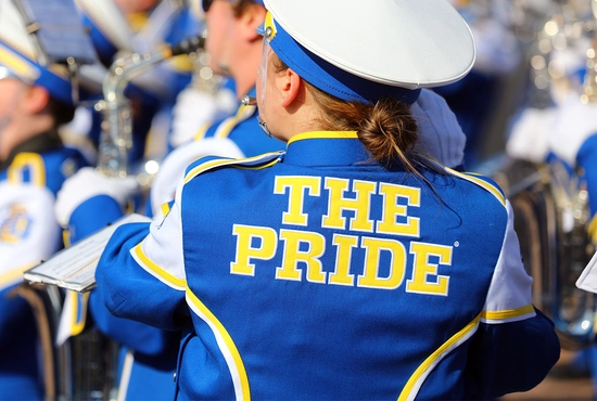 A member of The Pride of the Dakotas wearing a uniform, showcasing "The Pride" wording stitched onto the back of it.