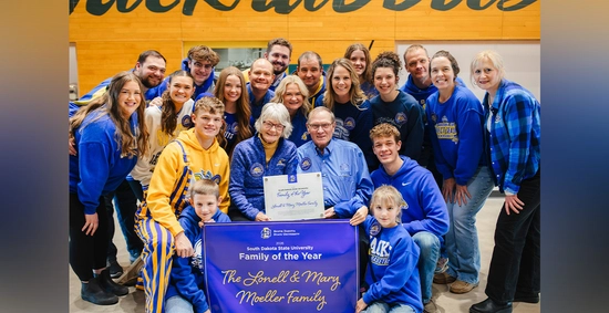 A large group of the Moeller Family, all wearing Jackrabbit gear, stands together holding a sign that says Family of the Year.