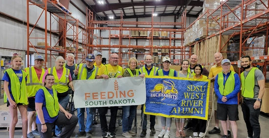 A large group of people gathers together for a photo after volunteering at Feeding South Dakota.