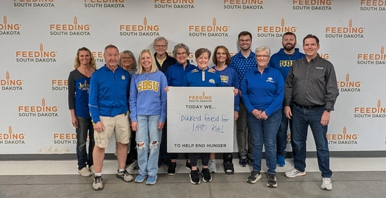 A group of people wearing SDSU clothing stands together after volunteering at Feeding South Dakota.