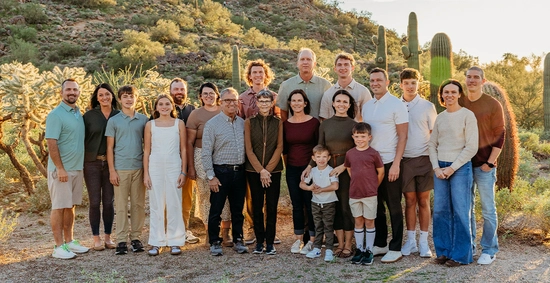 The Ramsdell family gathers together for a large group photo in a desert location with cacti behind them.