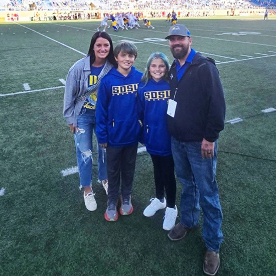 Members of the Ramsdell family smile together on the SDSU football field.