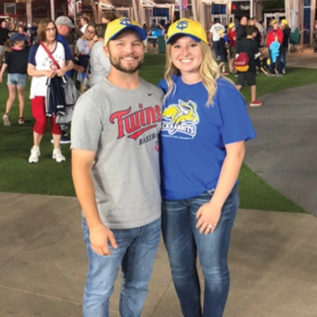 Brittney and her husband, Cody, wearing SDSU Twins baseball caps, stand together at Target Field.