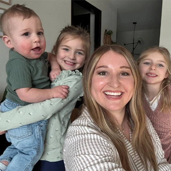 Brittney takes a selfie with her three young children indoors.