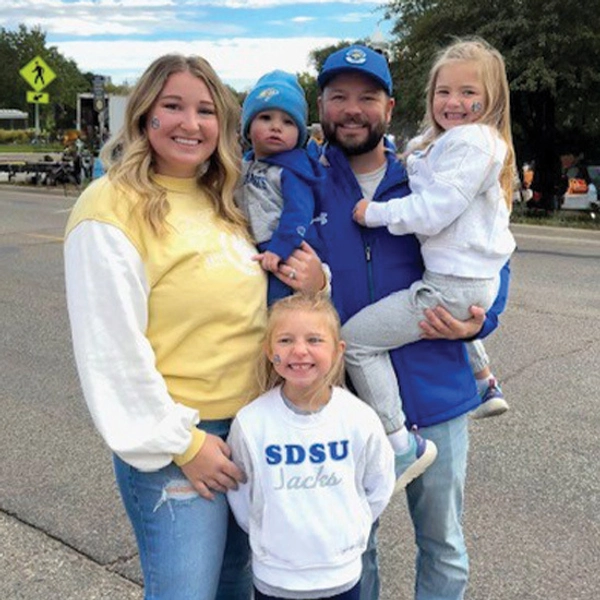 Brittney, her husband, and their three kids pose for a photo on SDSU's campus.