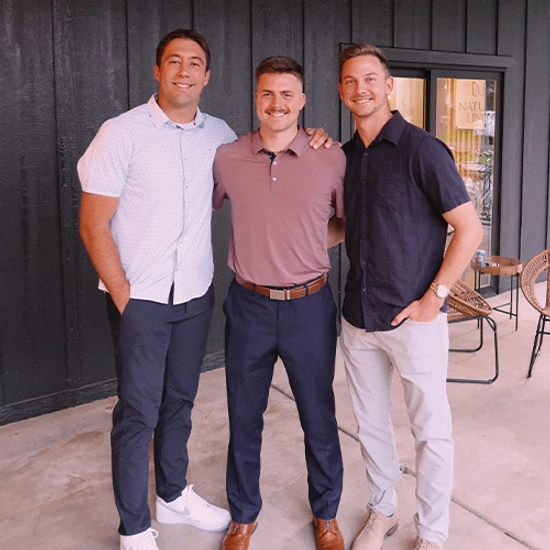 A photo of Trey with two friends smiling for the camera.