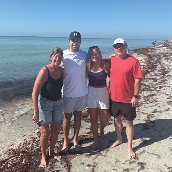 A photo of Trey, his parents, and his sister standing on a beach, smiling for the camera.